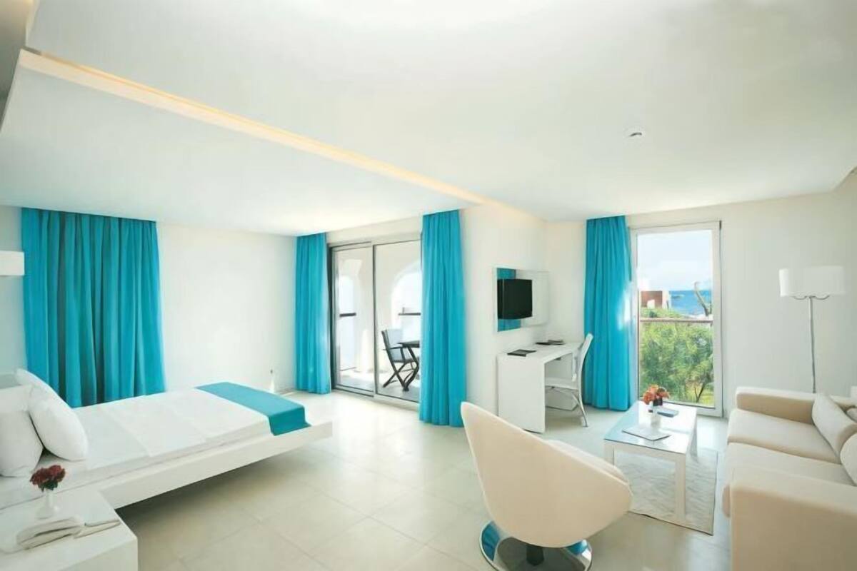 Habitación de hotel moderna con cama, escritorio, silla y vistas a través del ventanal.