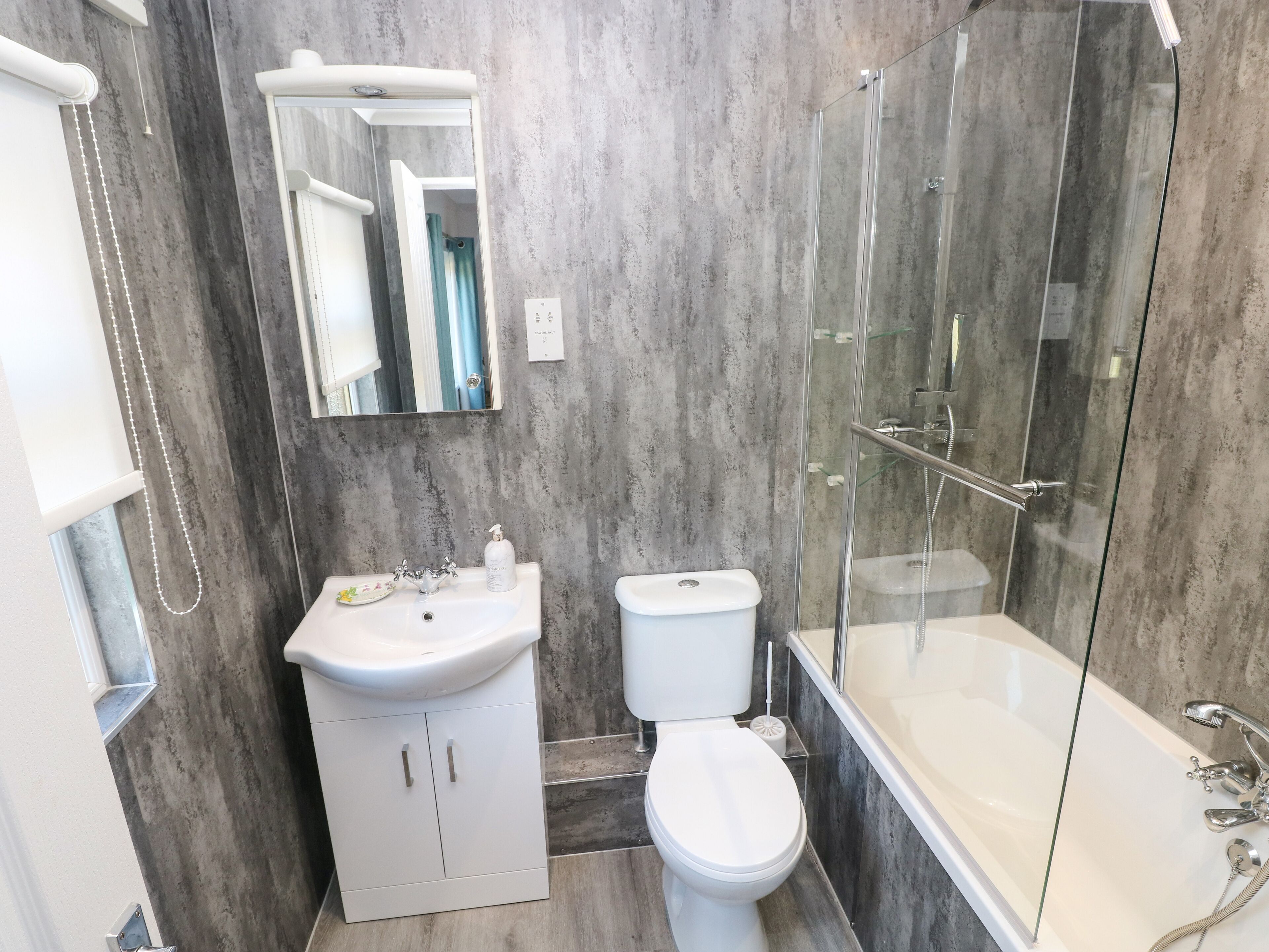Un baño moderno con ducha acristalada, lavabo blanco y retrete.
