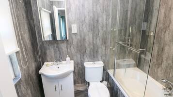 Un baño moderno con ducha acristalada, lavabo blanco y retrete.