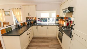 Een moderne keuken met witte kasten, een zwart aanrecht en uitzicht op buiten.