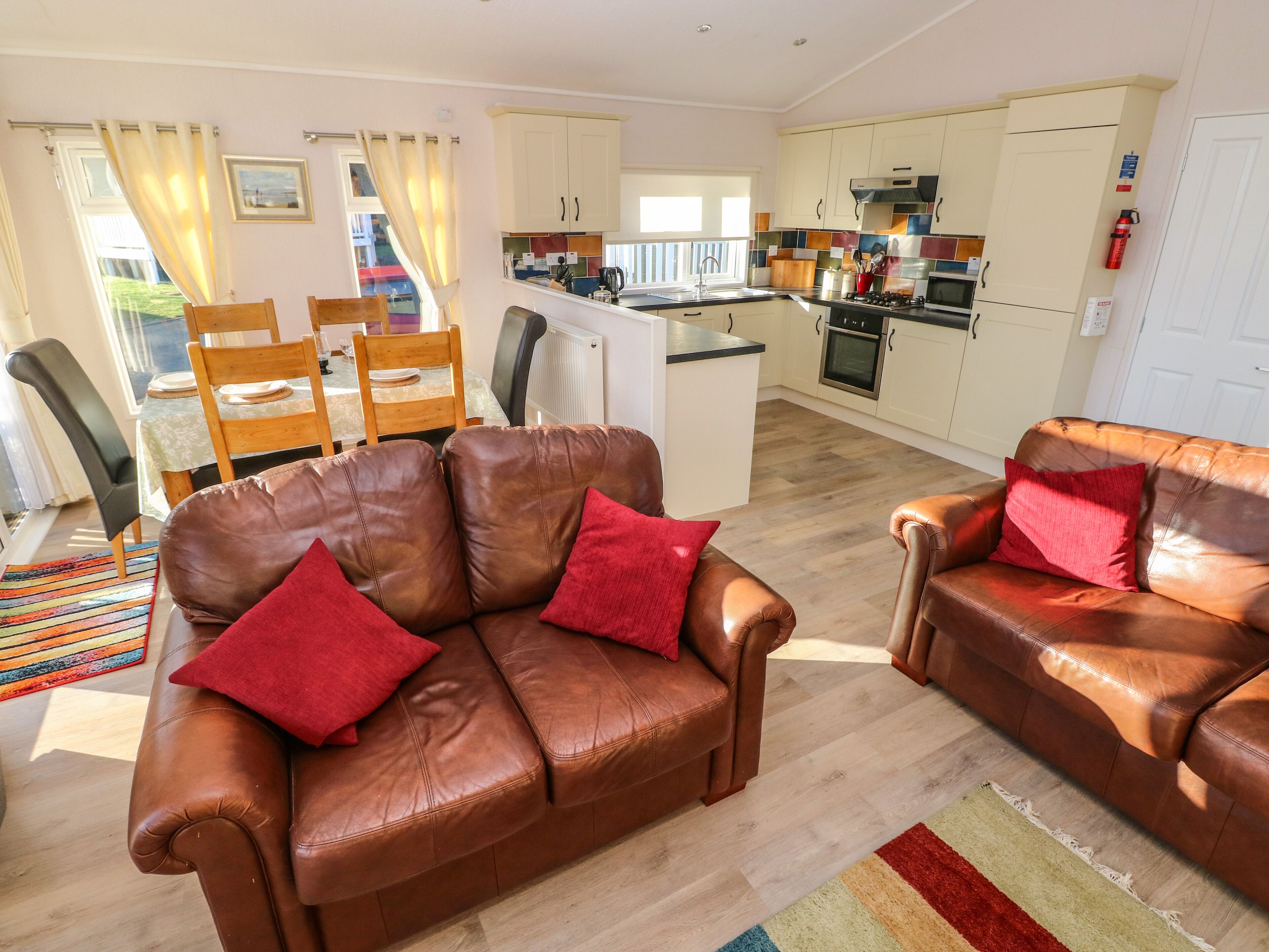 A living room with two brown leather sofas and a dining area with wooden chairs and a table.