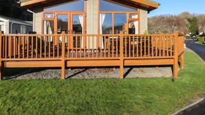 Een modern huis met een houten terras en grote ramen.