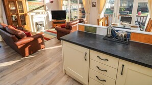 Een ruime woonkamer met een open haard, een leren bank en een eethoek met een tafel gedekt voor vier personen.
