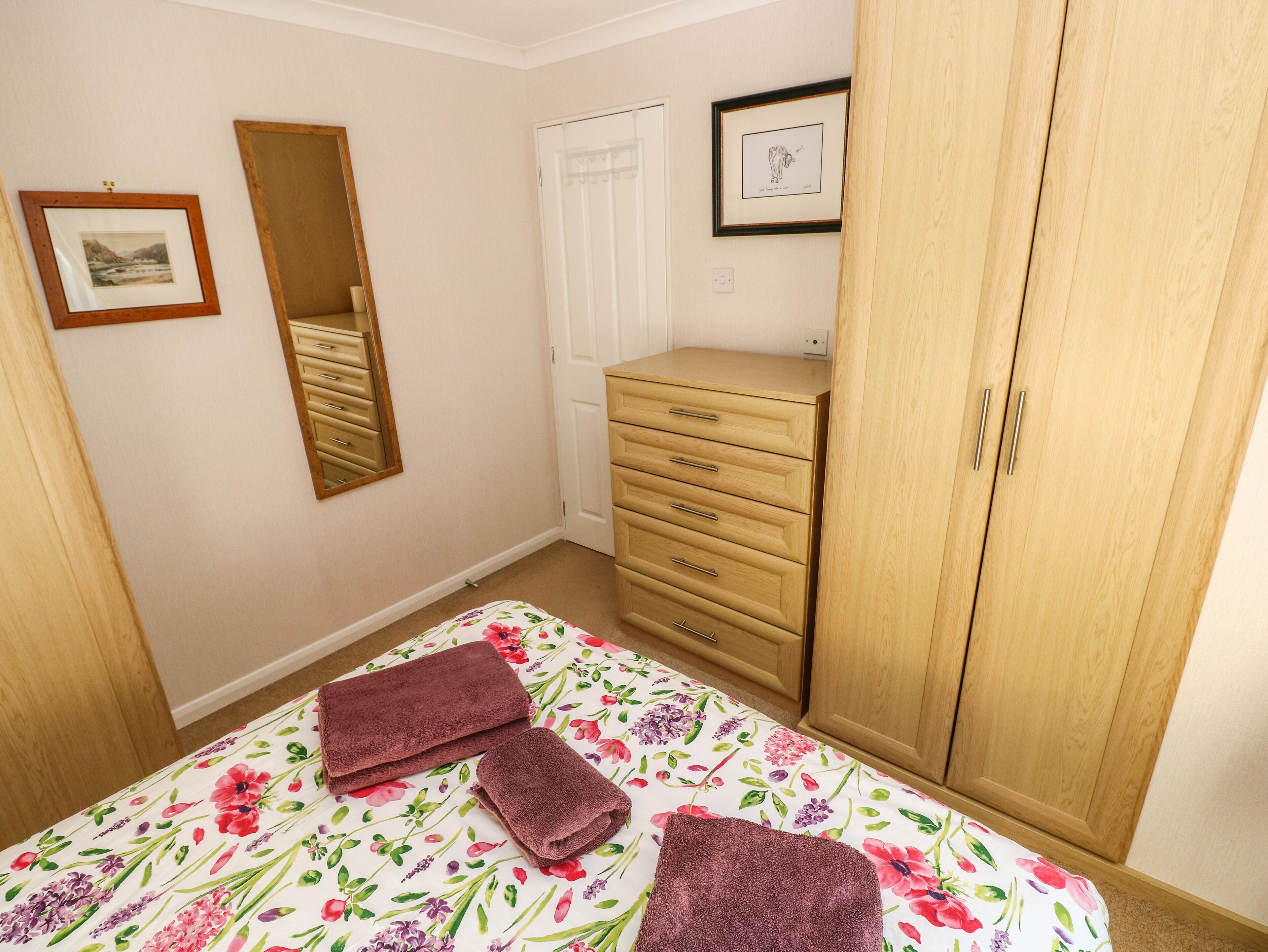 Un dormitorio con una cama, un aparador, un armario, un espejo y un cuadro en la pared.