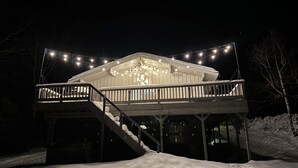 A snow-covered deck with a staircase leading to a building. - Bayou Chalet – Your Perfect Getaway Near Sugarbush Resort (Warren)
