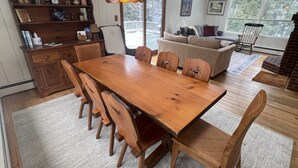 A dining area with a wooden table and chairs, a bookshelf, and a hanging light fixture. - Bayou Chalet – Your Perfect Getaway Near Sugarbush Resort (Warren)