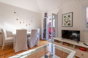 Un salon moderne comprenant un coin repas, un téléviseur et une table basse en verre.