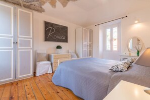 Une chambre à coucher comprenant un lit, une commode, une table de chevet, un miroir et un mur orné d’une inscription.