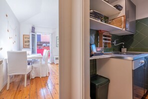 Eine kleine Küche mit Essbereich, Holzboden und Blick in den Wohnraum.