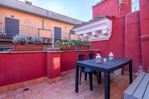 Une terrasse avec une table et des chaises, des plantes en pot et un mur rouge.