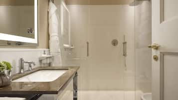 A modern bathroom with a glass-enclosed shower, a marble sink, and a large mirror.