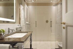 A modern bathroom with a glass-enclosed shower, a marble sink, and a large mirror.