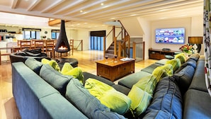 A modern living room with a fireplace, a dining area, and a kitchen in the background. - Bretherdale Barn (Bretherdale)