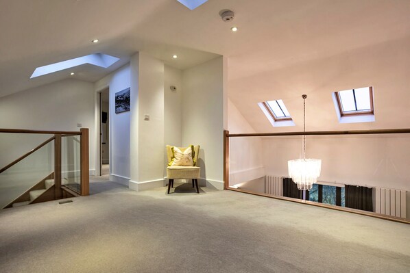 A spacious loft with a high ceiling, skylights, a chandelier, and a cozy seating area. - Bretherdale Barn (Bretherdale)