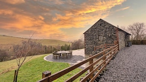 A stone building with a wooden deck and a circular seating area. - Bretherdale Barn (Bretherdale)