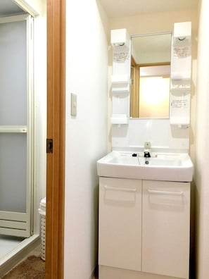 Un baño con lavamanos blanco, espejo y dos armarios.