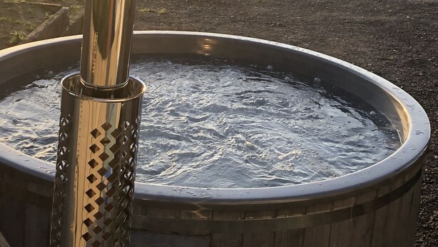 Un bain à remous avec un poteau métallique au premier plan et un paysage rural en arrière-plan.