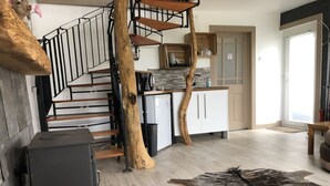 Une cuisine moderne avec un escalier en bois, un réfrigérateur et un coin repas agrémenté d’un tapis et d’une peau de bête.