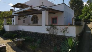 A two-story house with a covered patio and a stone wall. - Two-bedroom apartment with extra beds - Alba 6 (Khamma)