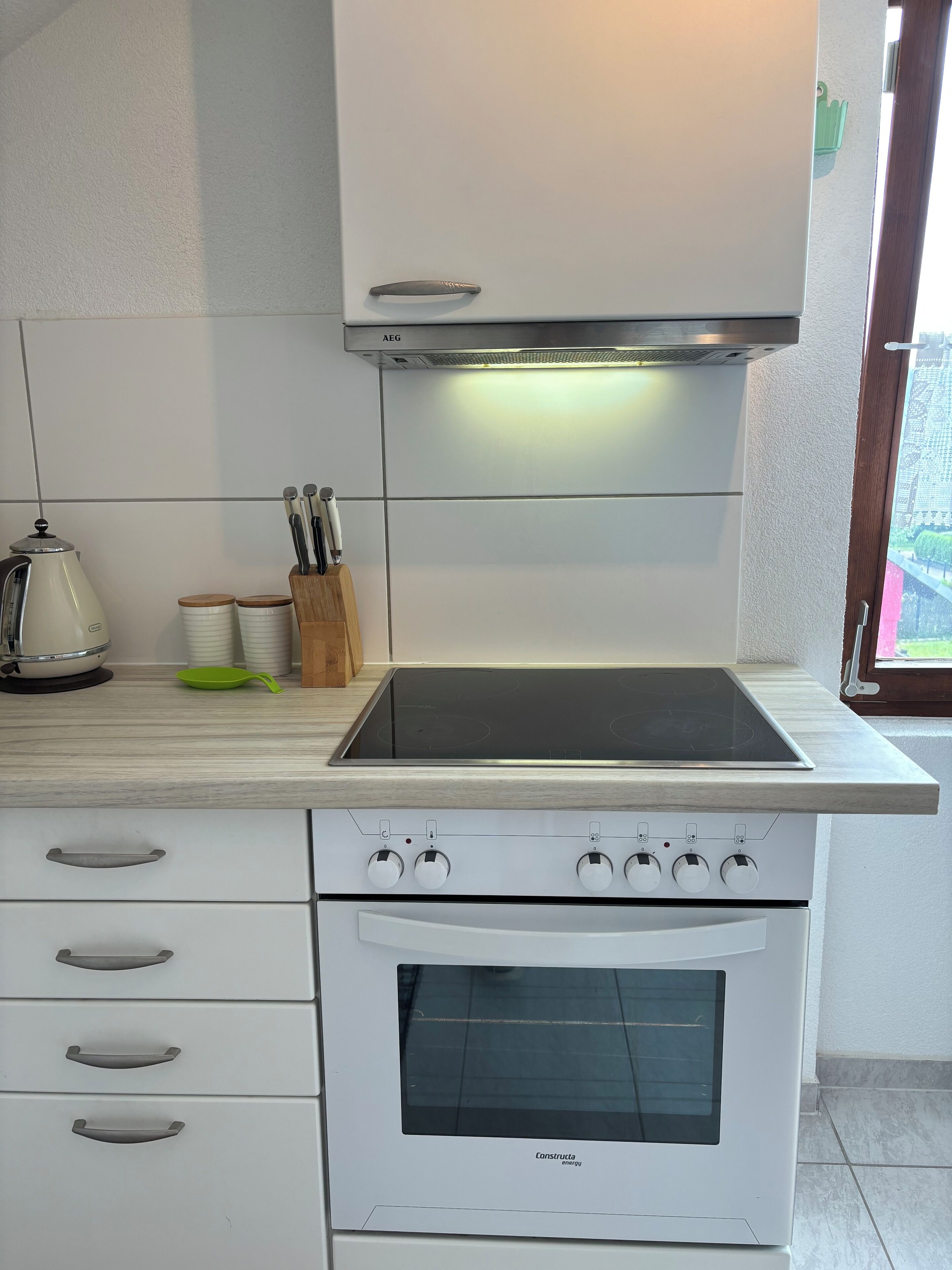 A kitchen with white cabinets, a stove, and a window.