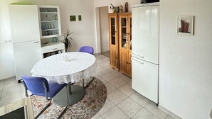 Une cuisine de taille réduite avec une table ronde, des chaises bleues et un réfrigérateur.
