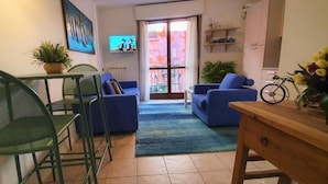 Ein Wohnzimmer mit Essbereich, einem an der Wand montierten Fernseher und einem Balkon mit Blick.