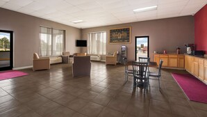 Um amplo saguão de hotel com área de estar, mesa de jantar e cozinha.