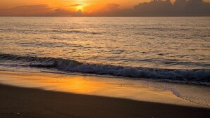 Una spiaggia al tramonto con le onde che si infrangono sulla riva.
