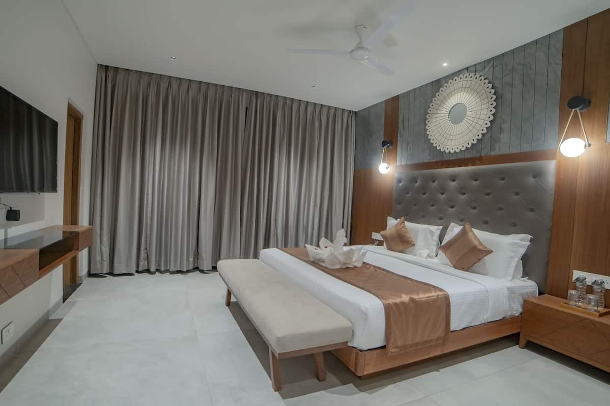 Quarto moderno com uma cama grande, uma mesa de cabeceira, televisão na parede e um ventilador de teto.
