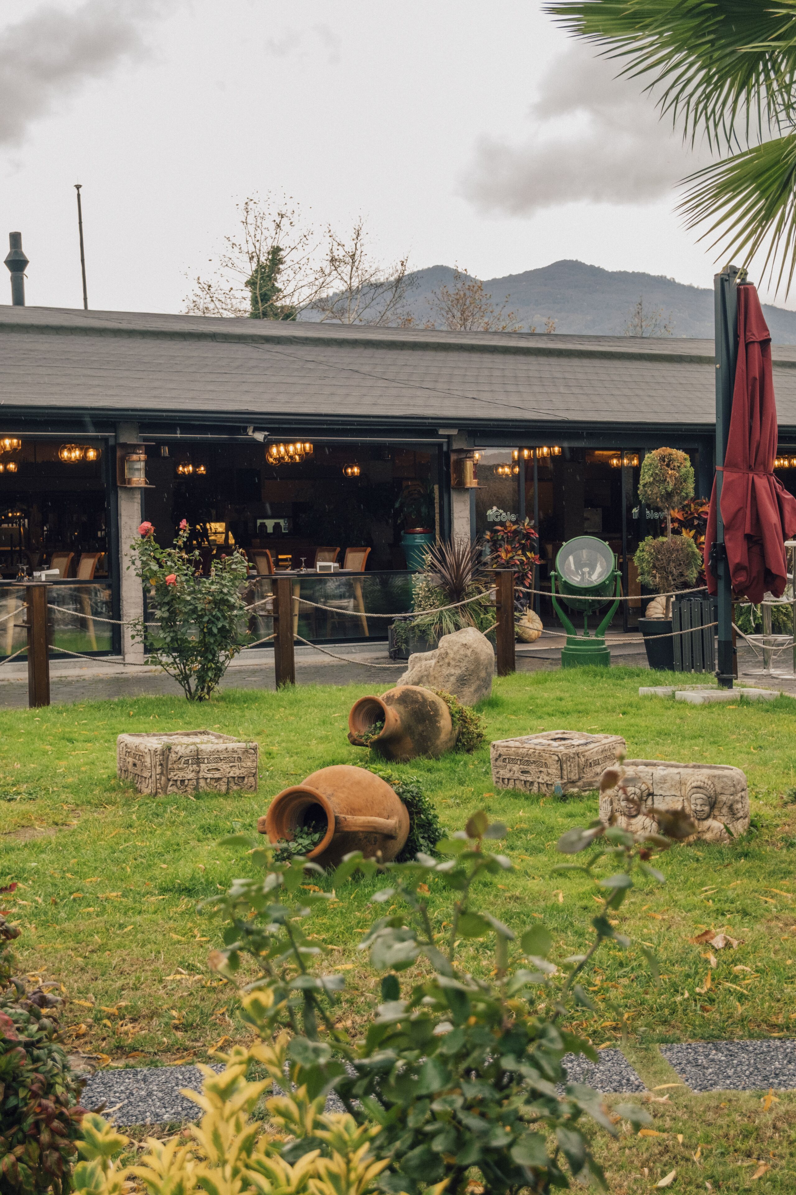Un restaurant avec une terrasse, une vue sur les montagnes et un palmier.