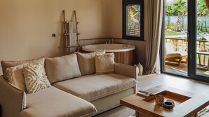 A modern living room with a sectional sofa, a wooden coffee table, and a large window with a view of the outdoors. - Gölevi Resort Sapanca (Sapanca)