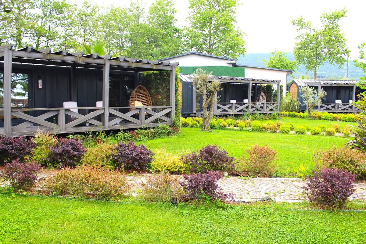 A garden with a gazebo, a covered seating area, and a small building.
