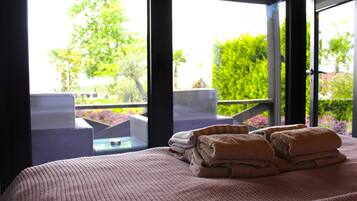 Relax in a serene space with a large bed, lush views, and access to the pool.