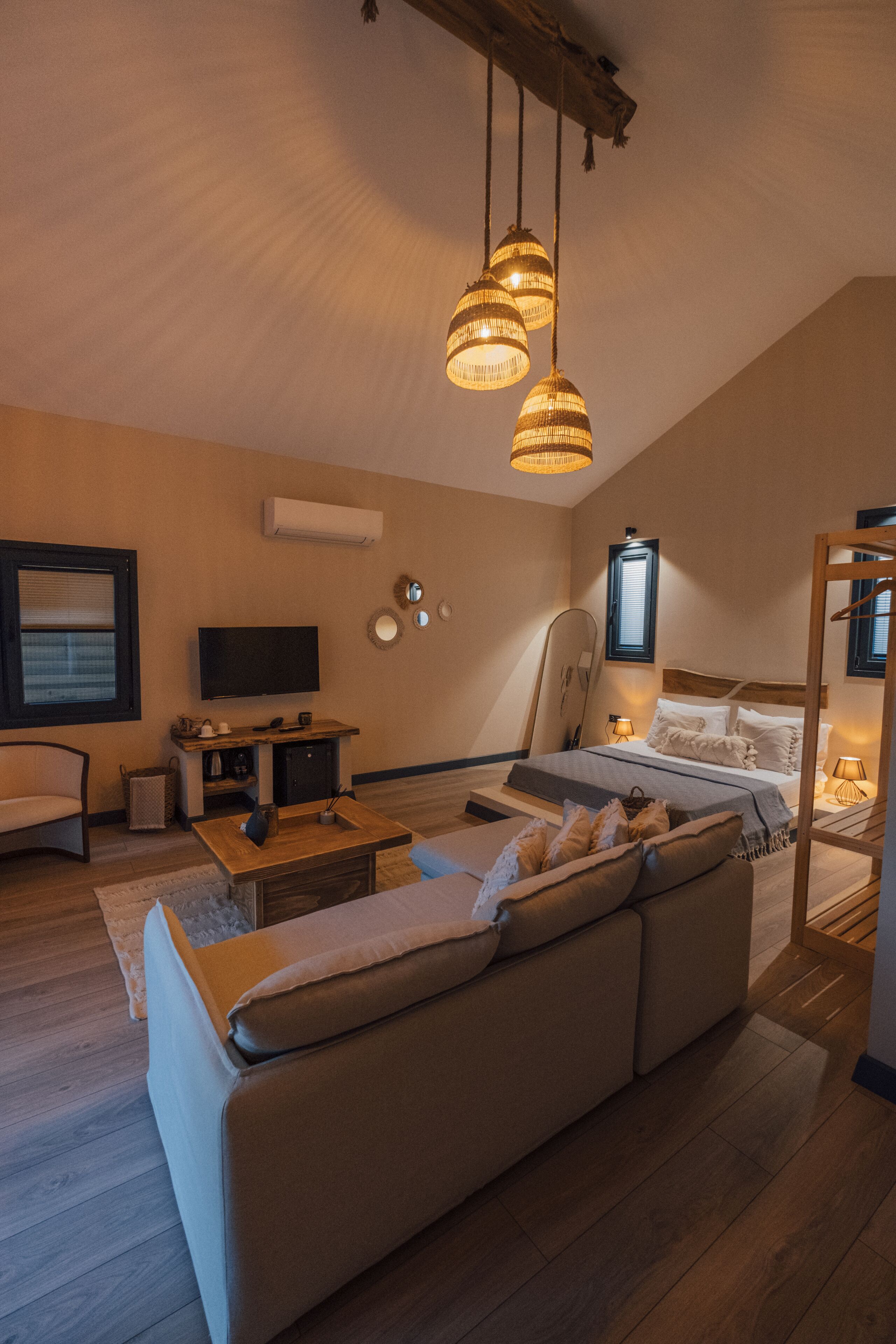 A modern bedroom with a large bed, a sofa, a TV, and a ceiling fan.