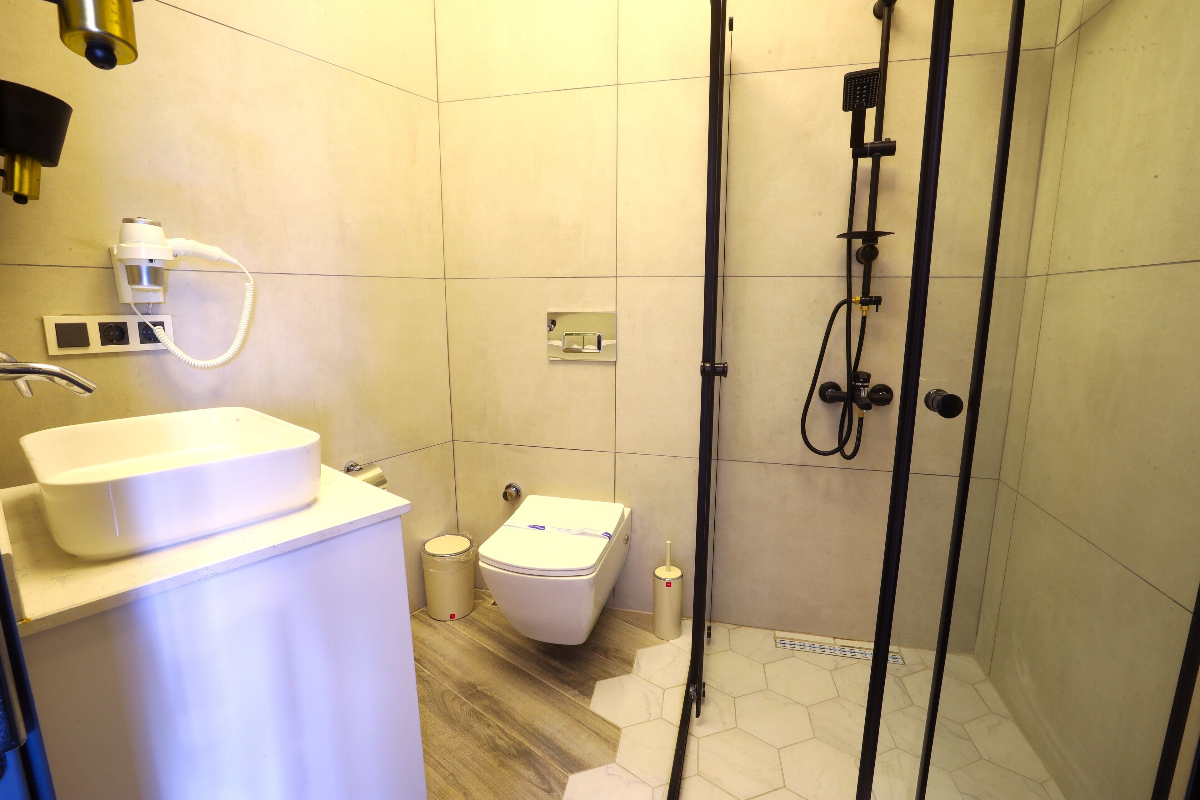 Et badeværelse med hvid vask, toilet og brusebad.