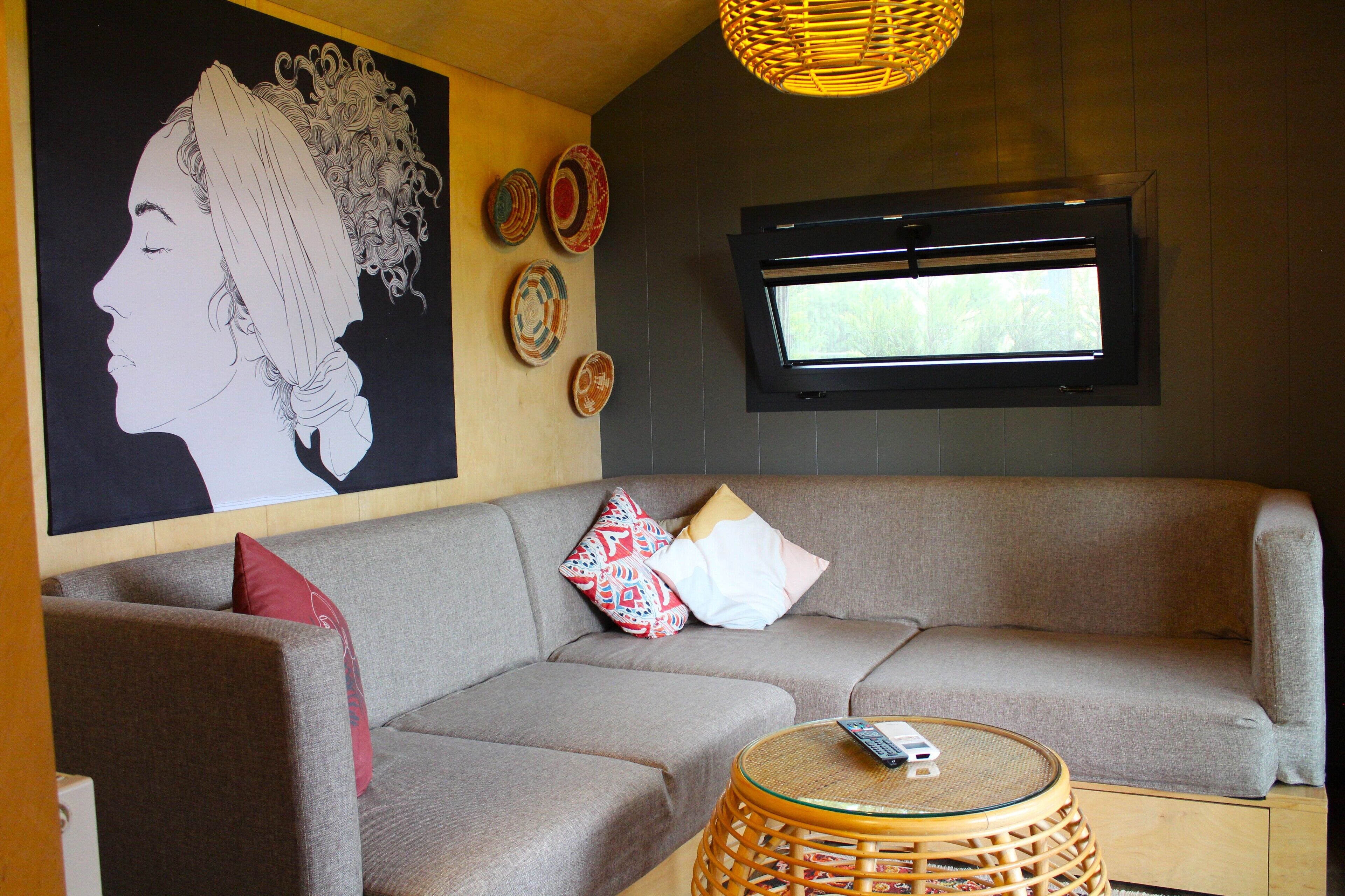 A modern living area with a sofa, a round wicker table, and a wall-mounted TV.