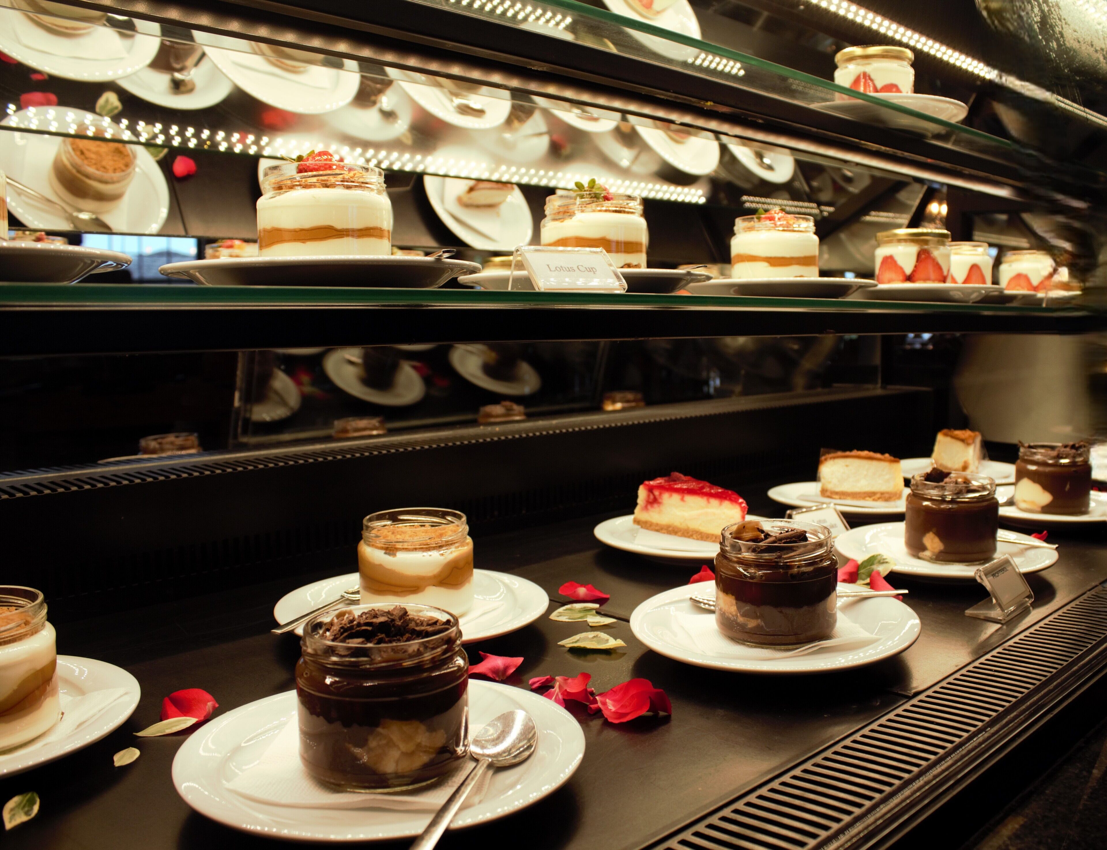 Una presentación de postres con varios pasteles y dulces en platos, algunos con chocolate y fresas.