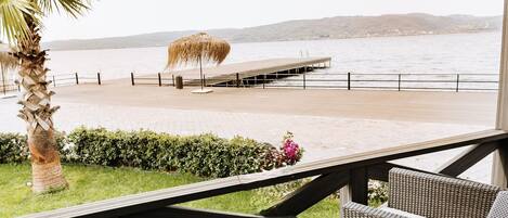 An outdoor patio with wicker furniture, a palm tree, and a view of the sea.