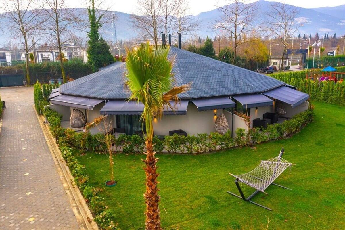 A modern house with a sloped roof, surrounded by a well-maintained lawn and a hammock.