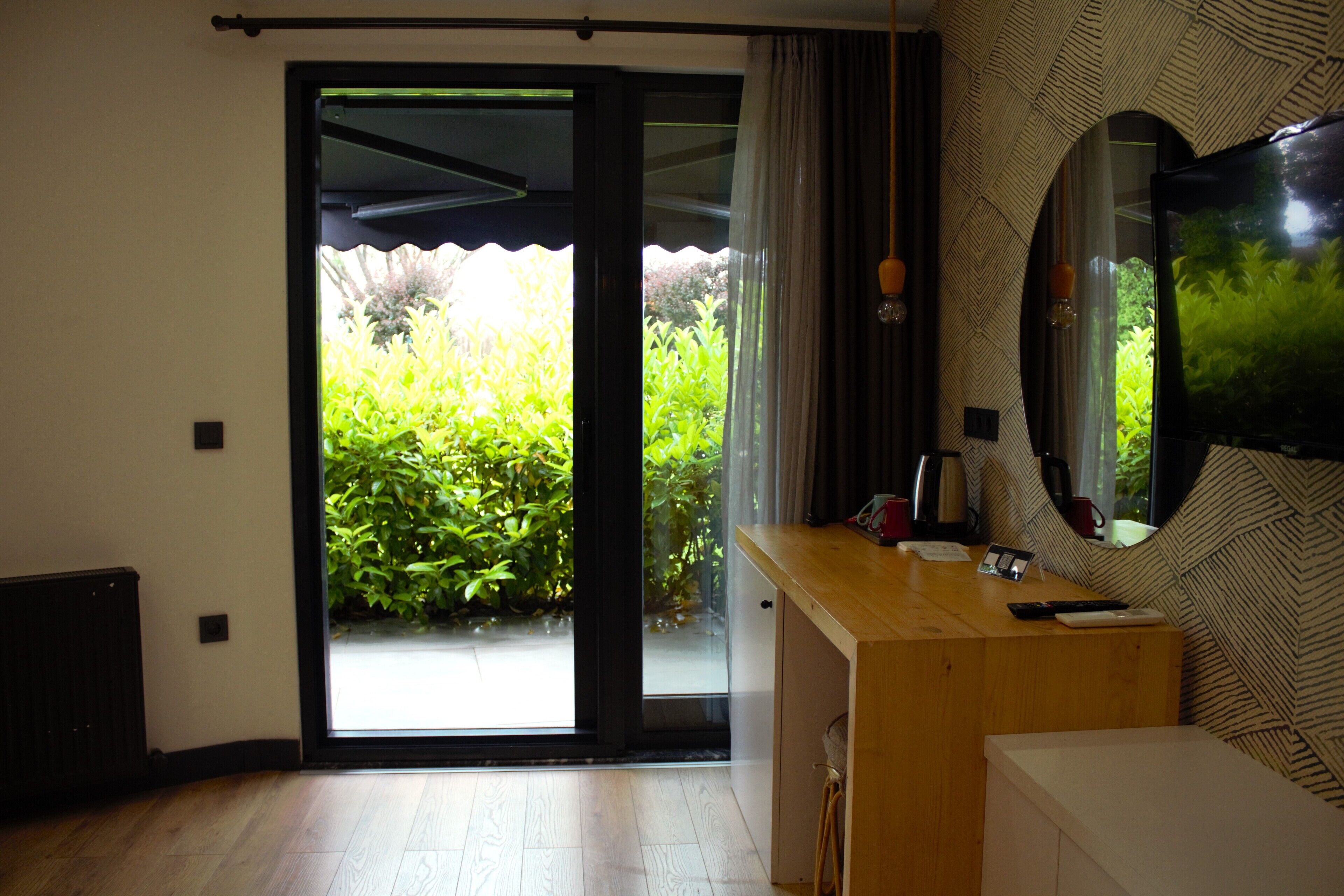 Un baño moderno con tocador de madera, un espejo grande y puerta corrediza de vidrio que da a un jardín.