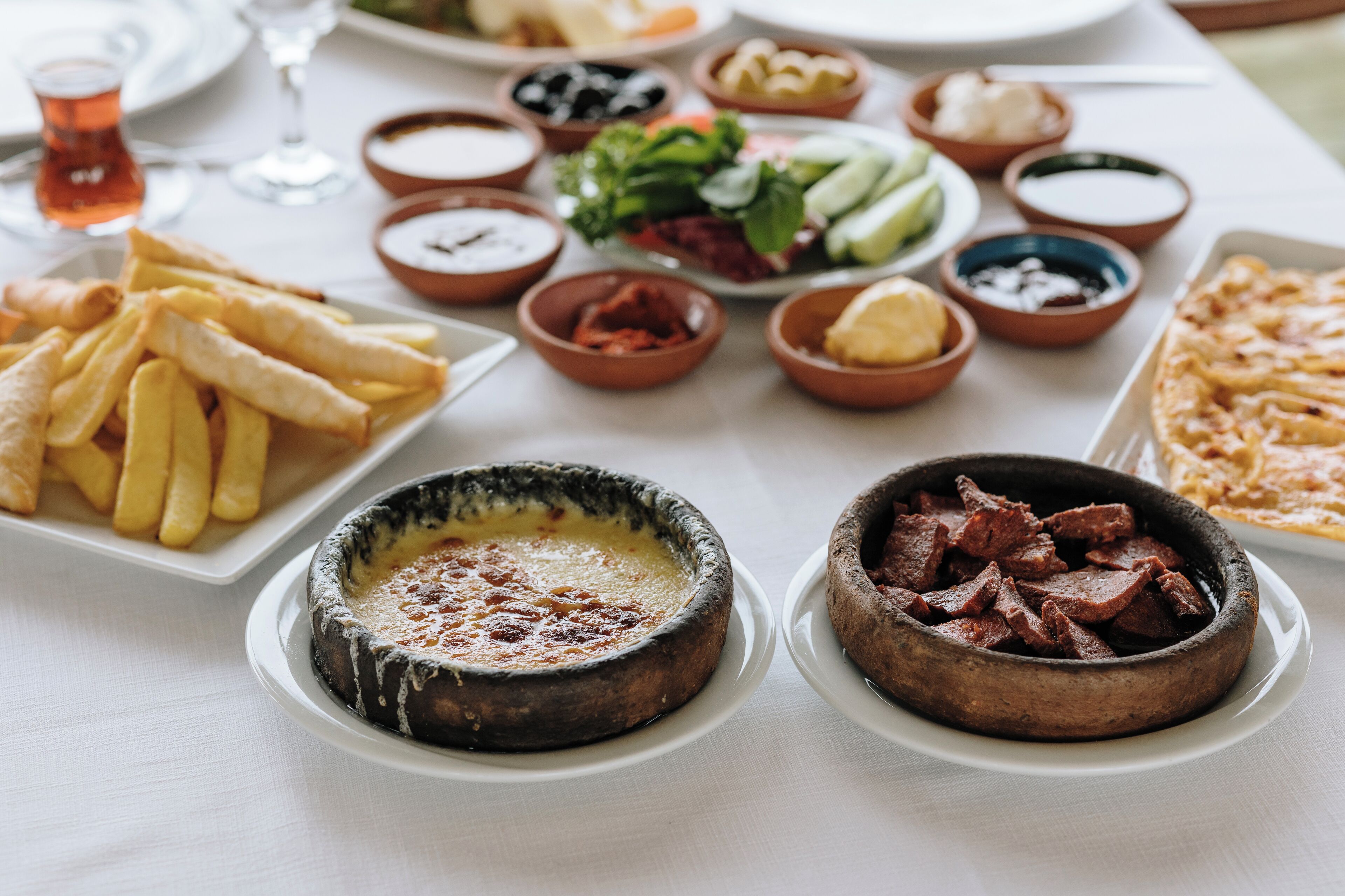 A table set with various dishes including fries, a dessert, and meat.