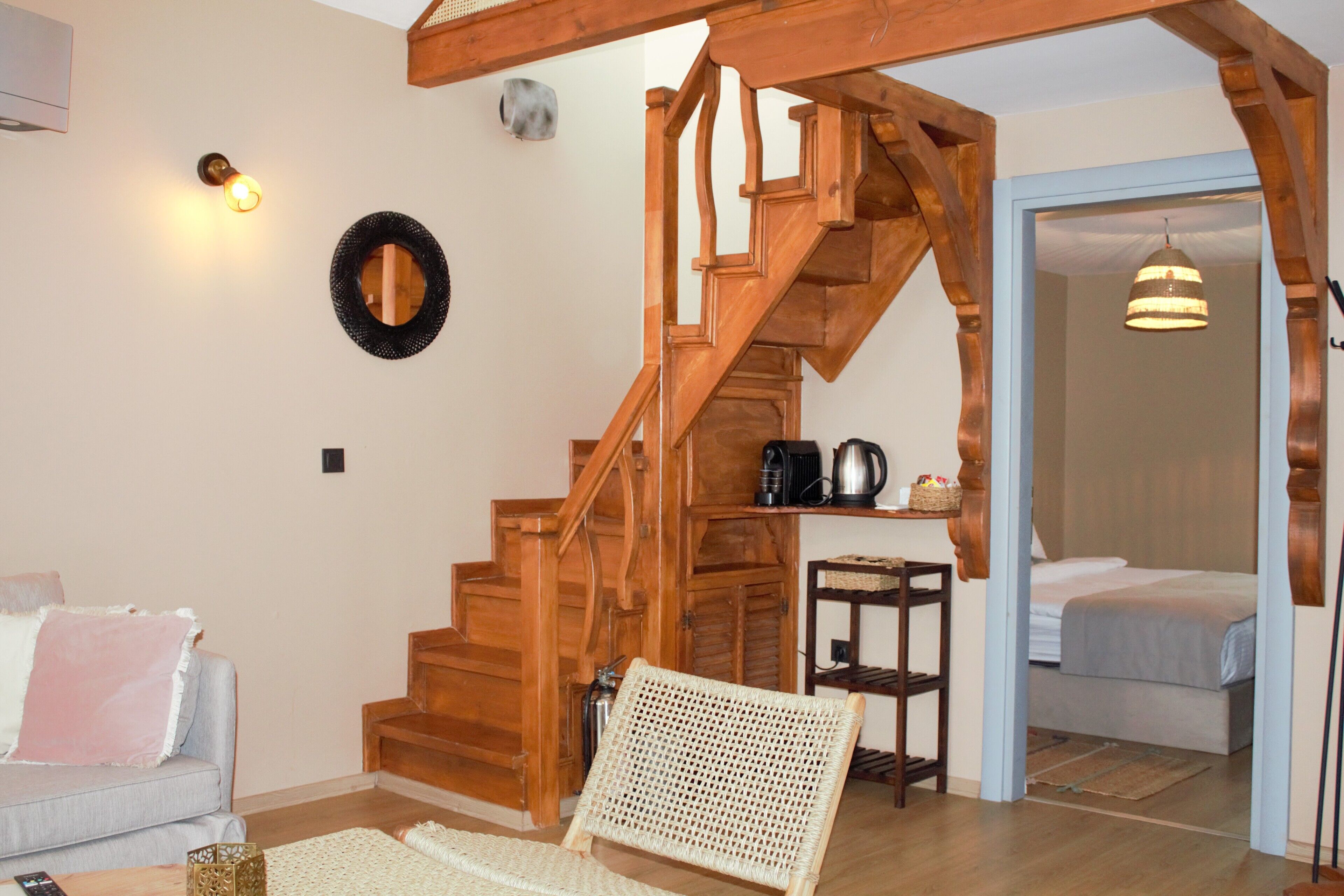 A wooden staircase leading to a bedroom with a bed and a hanging light fixture.