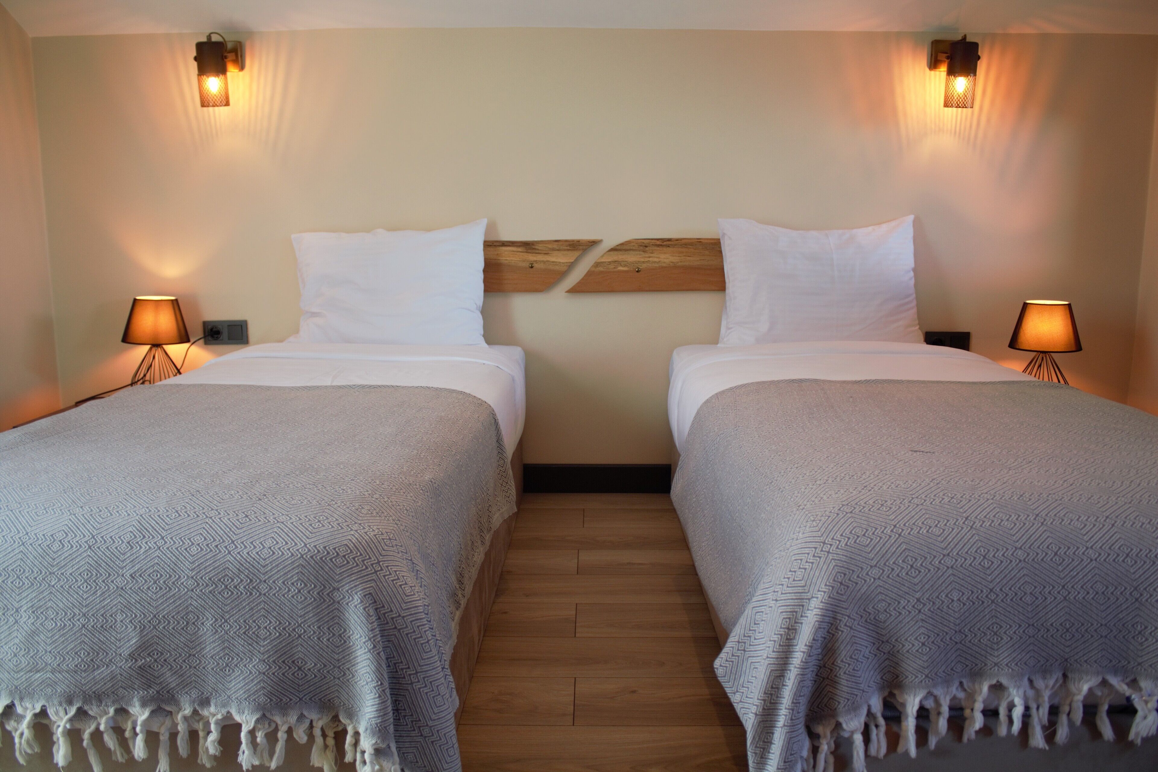 A room with two beds, each with a headboard, bedside lamps, and a patterned bedspread.