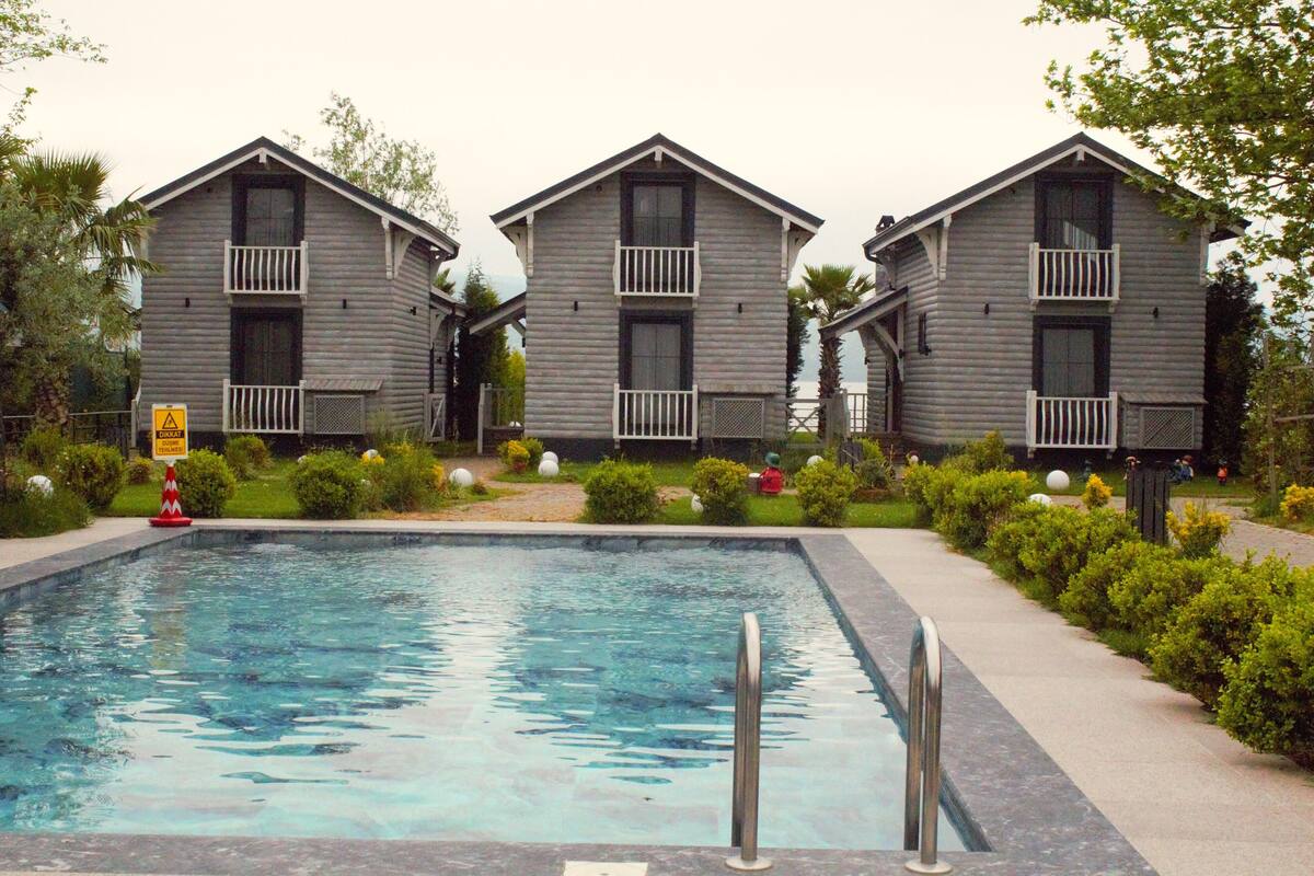 A pool area with three wooden buildings, each with a balcony.
