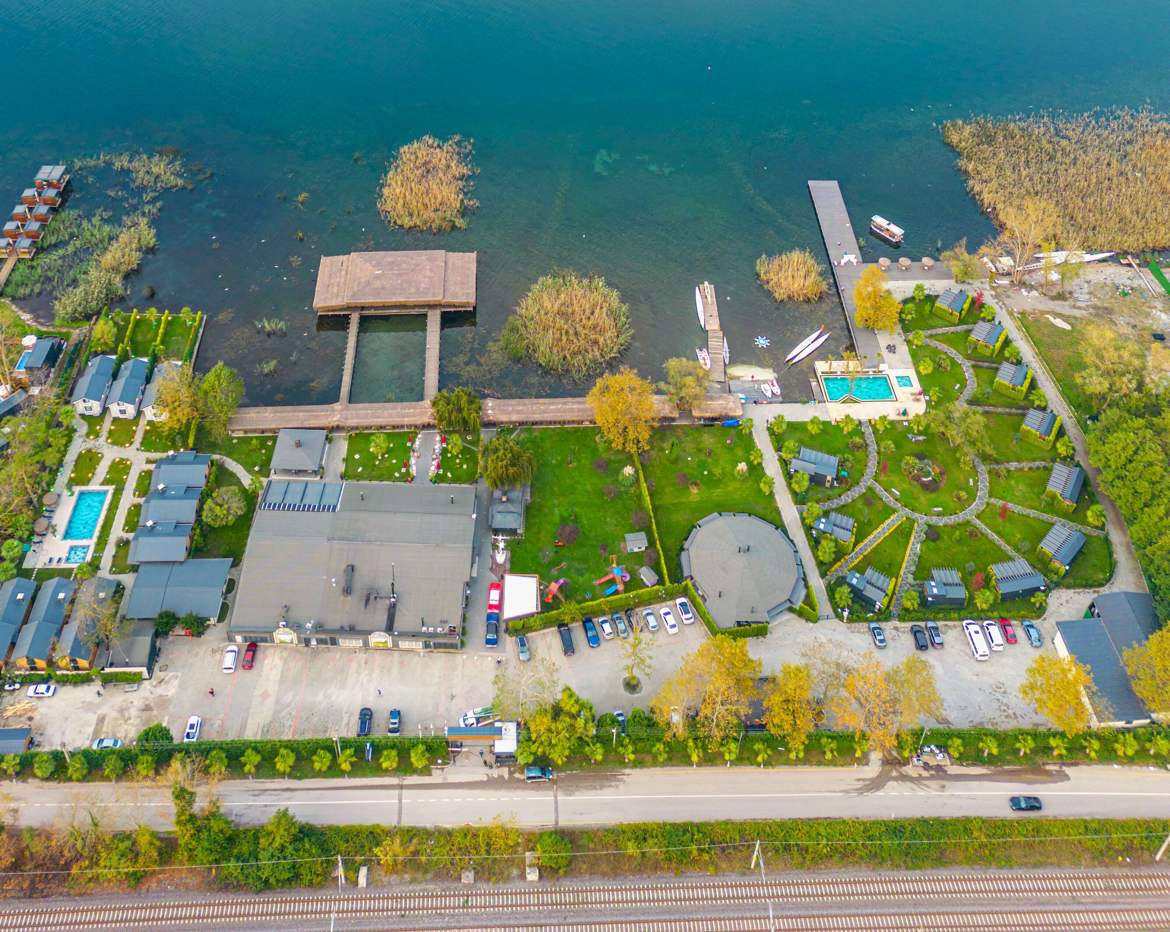 An aerial view of a resort with a swimming pool, a dock, and a circular lawn area.