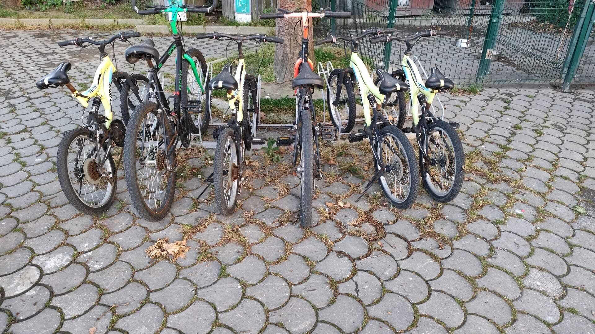 Un aparcamiento para bicicletas con cuatro bicicletas estacionadas sobre una superficie pavimentada.