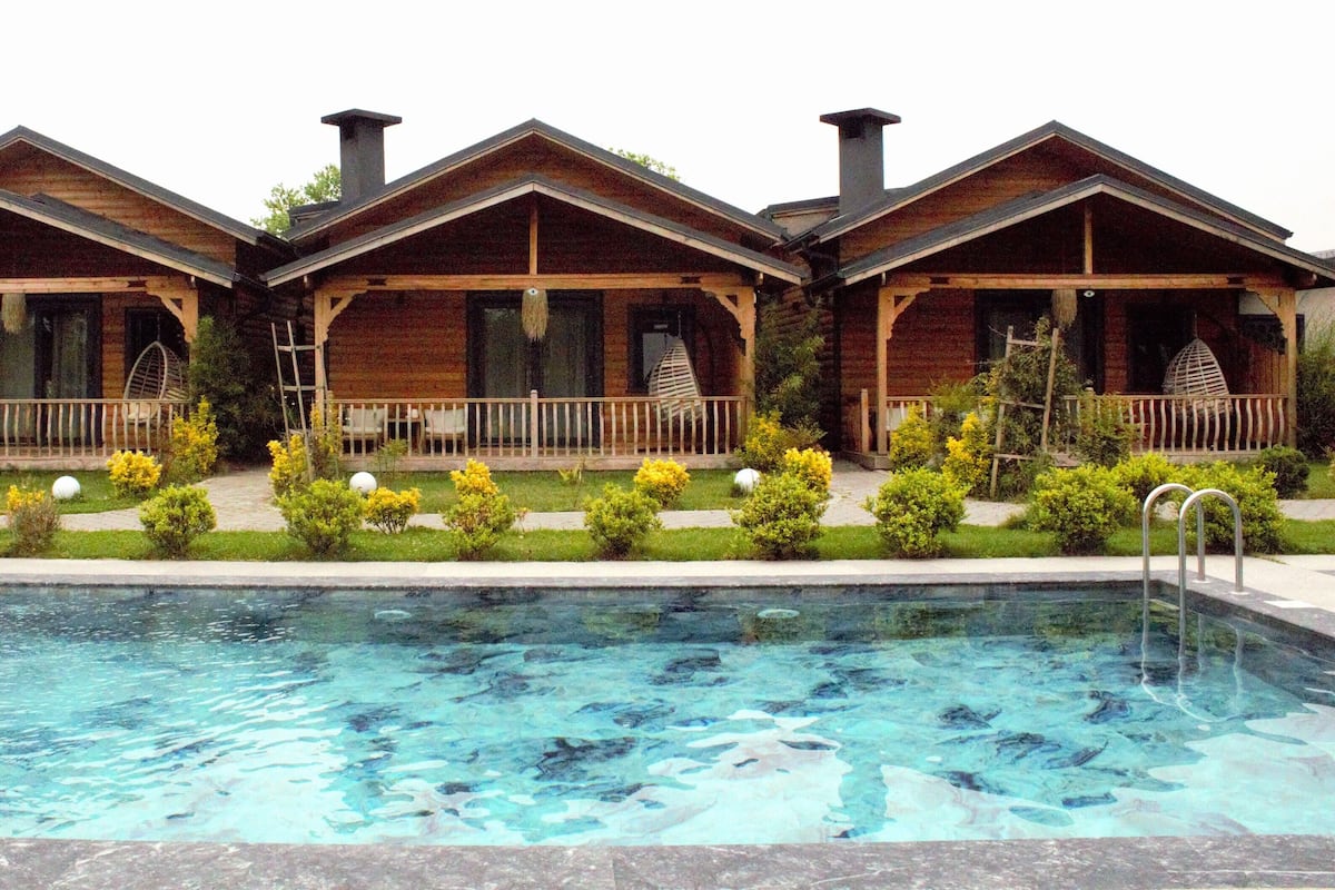 A row of log cabin-style cabins with a swimming pool in front.