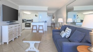 Ein modernes Wohnzimmer mit einem blauen Sofa, einem Holztisch und einem an der Wand montierten Fernseher.