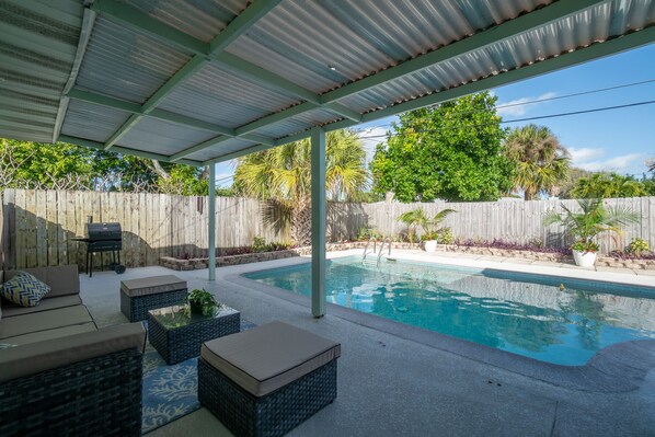Relax by the pool surrounded by lush greenery and comfortable wicker furniture.