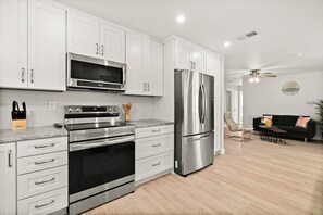 Enjoy cooking in this well-equipped kitchen with stainless steel appliances, white cabinetry, and a granite countertop.